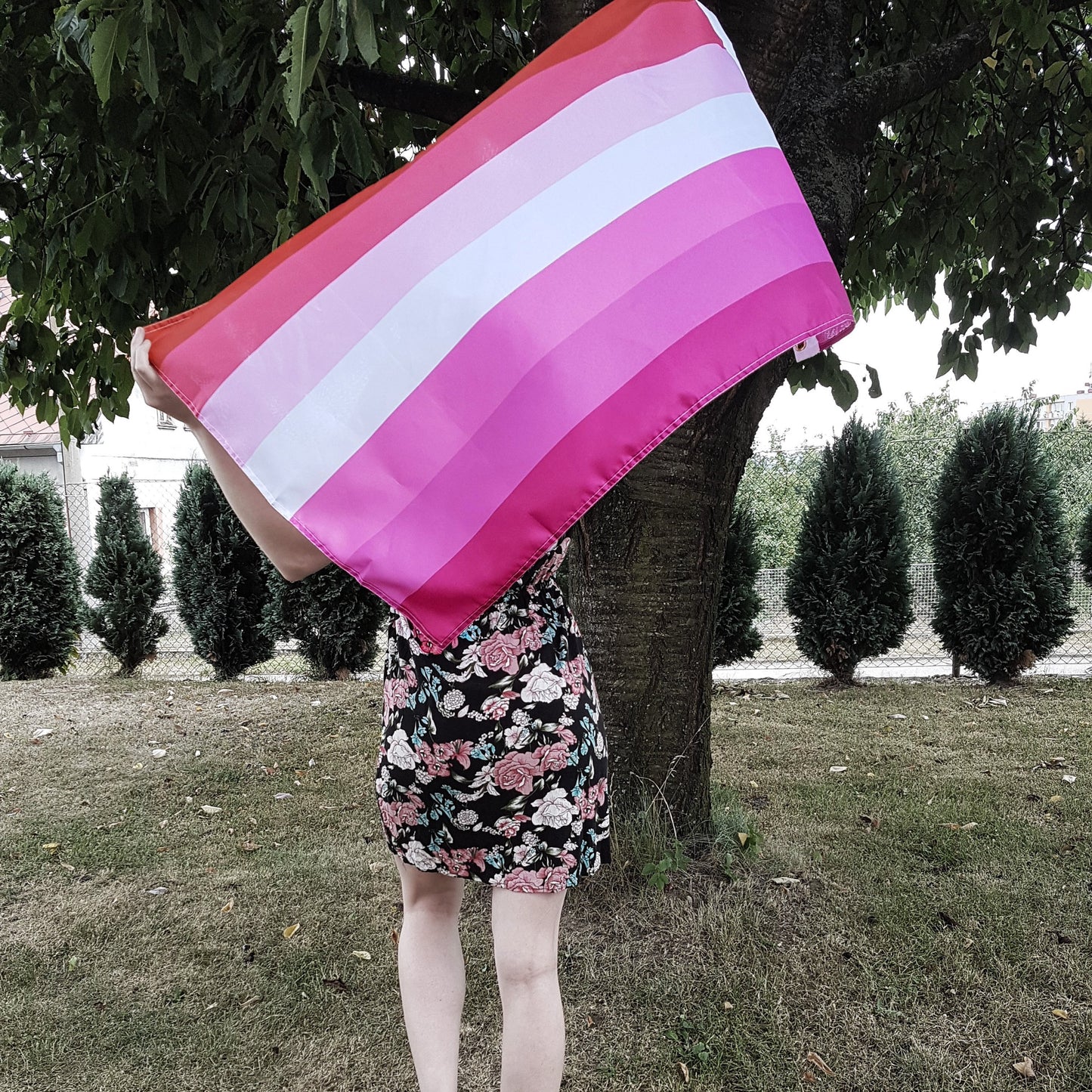 Woman holding Lesbian Pink Flag behind herself